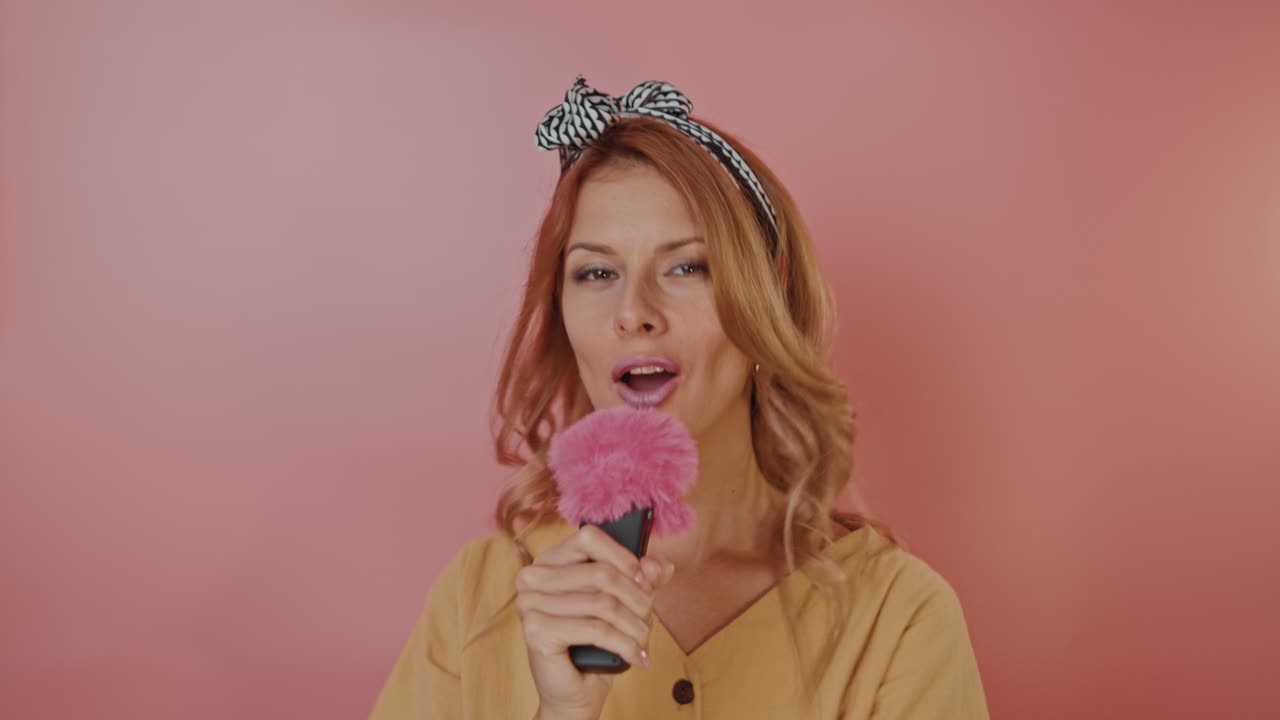 Pembe mikrofona şarkı söyleyen kadın