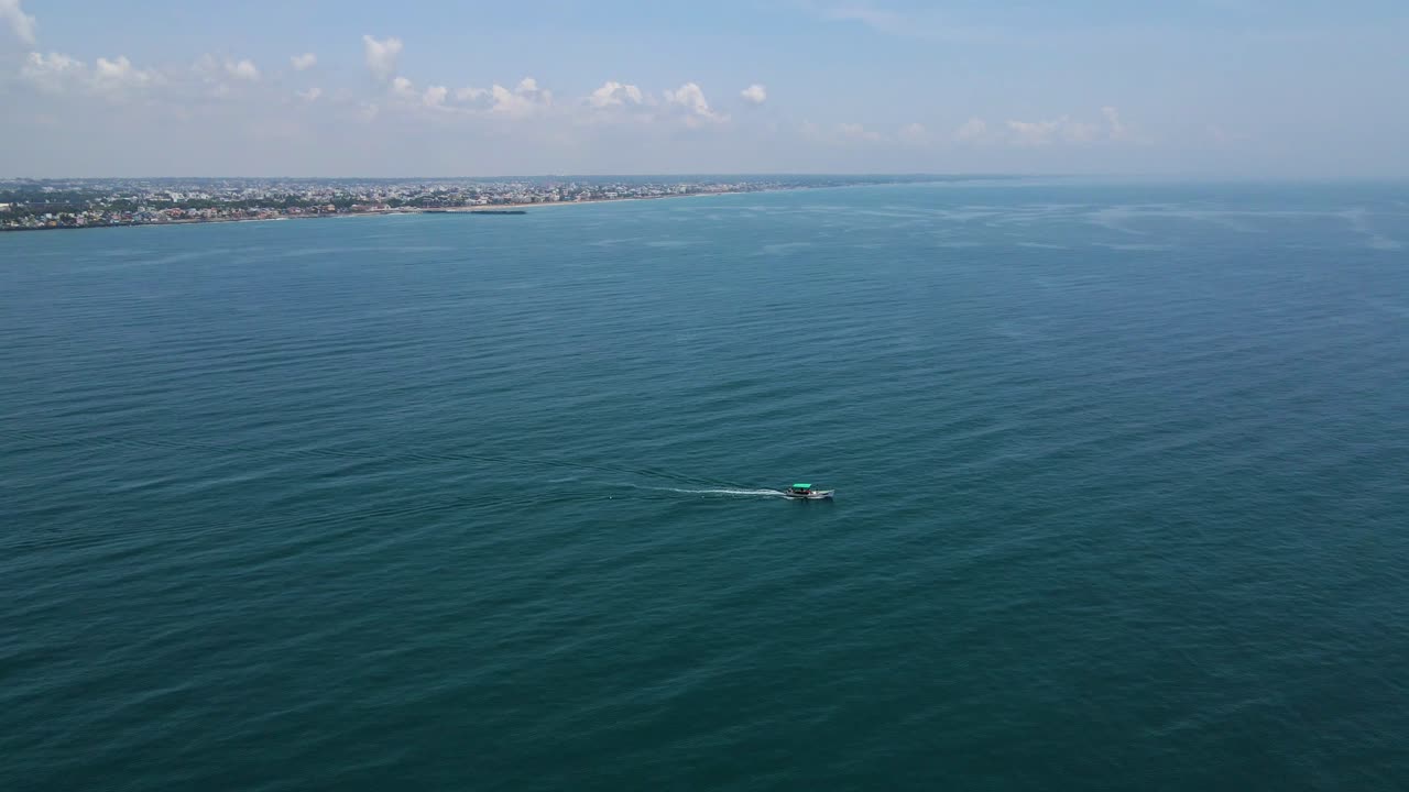 Aerial drone shot highlighting the tiny fisher boat amidst the seemingly endless ocean waves.