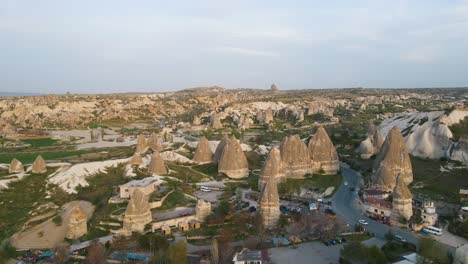 Toma-Aérea-De-Hermosas-Chimeneas-De-Hadas-Junto-Con-Casas-Residenciales-En-Capadocia,-Turquía-Durante-La-Noche