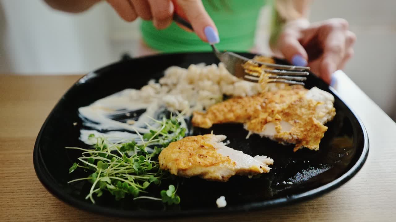 Healthy homemade chicken lunch with greens and rice on black ceramic plate