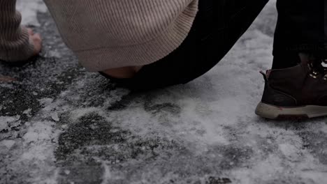 person slips on ice and falls to ground in slow motion, hurt ankle and hand closeup