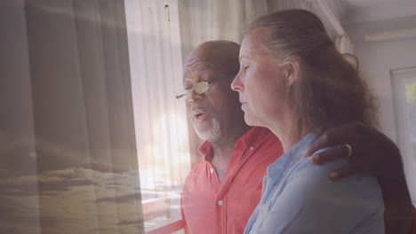 couple gazing out window, serene sky overlay creating animation effect