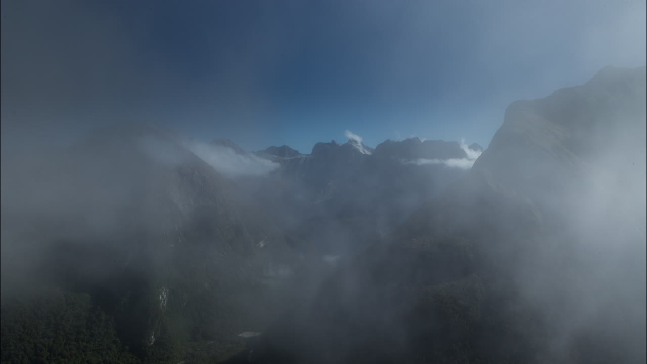 Time lapse of heavy fog moving through the rugged mountains deep in Fjiordland National Park, New Zealand
