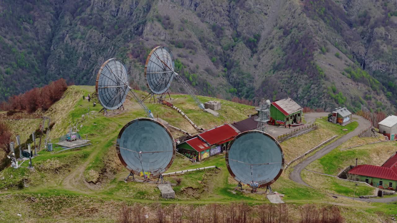 Old radar station on a green mountain ridge, peaceful and remote aerial view