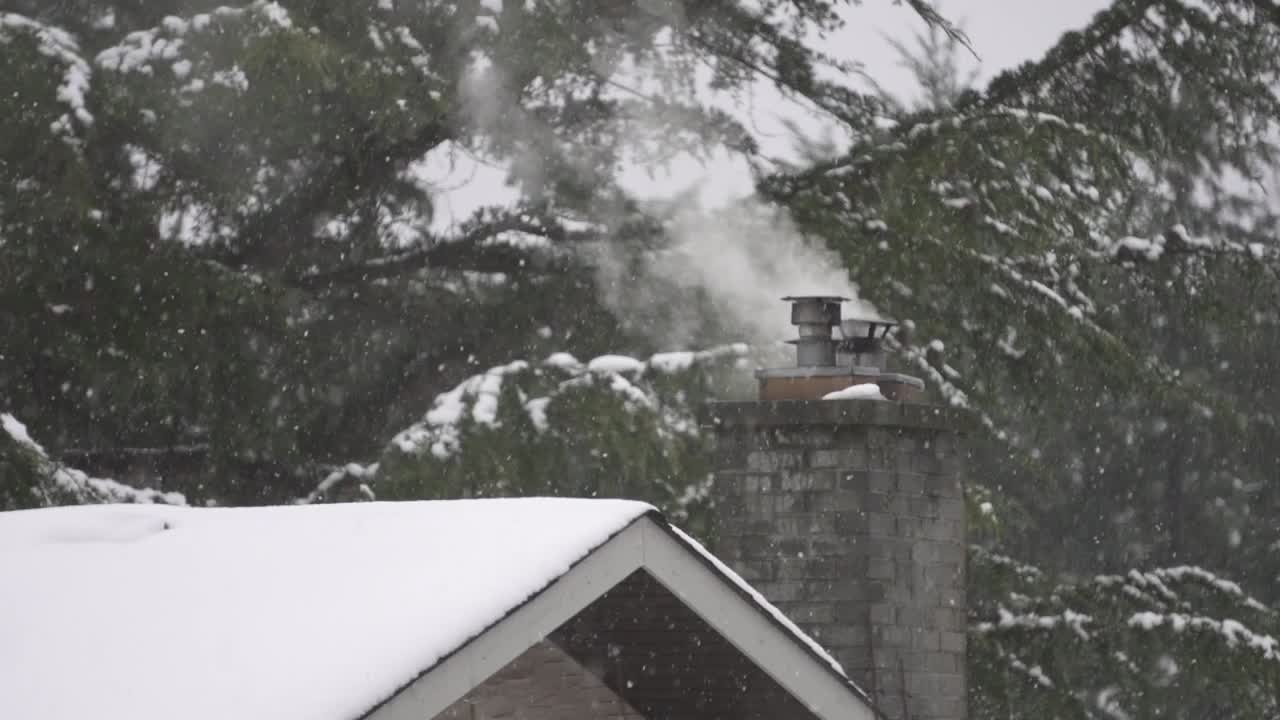 Slow-motion footage of a smoking chimney during a light snowfall in Canada