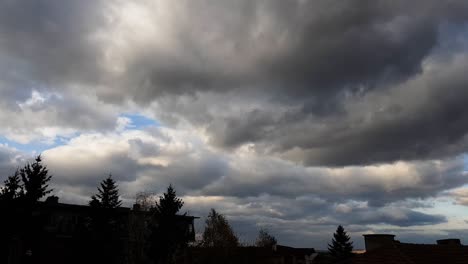 nubes oscuras arrastradas por el viento sobre edificios y árboles - ángulo bajo, lapso de tiempo