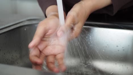 washing hands under a tap in a kitchen sink