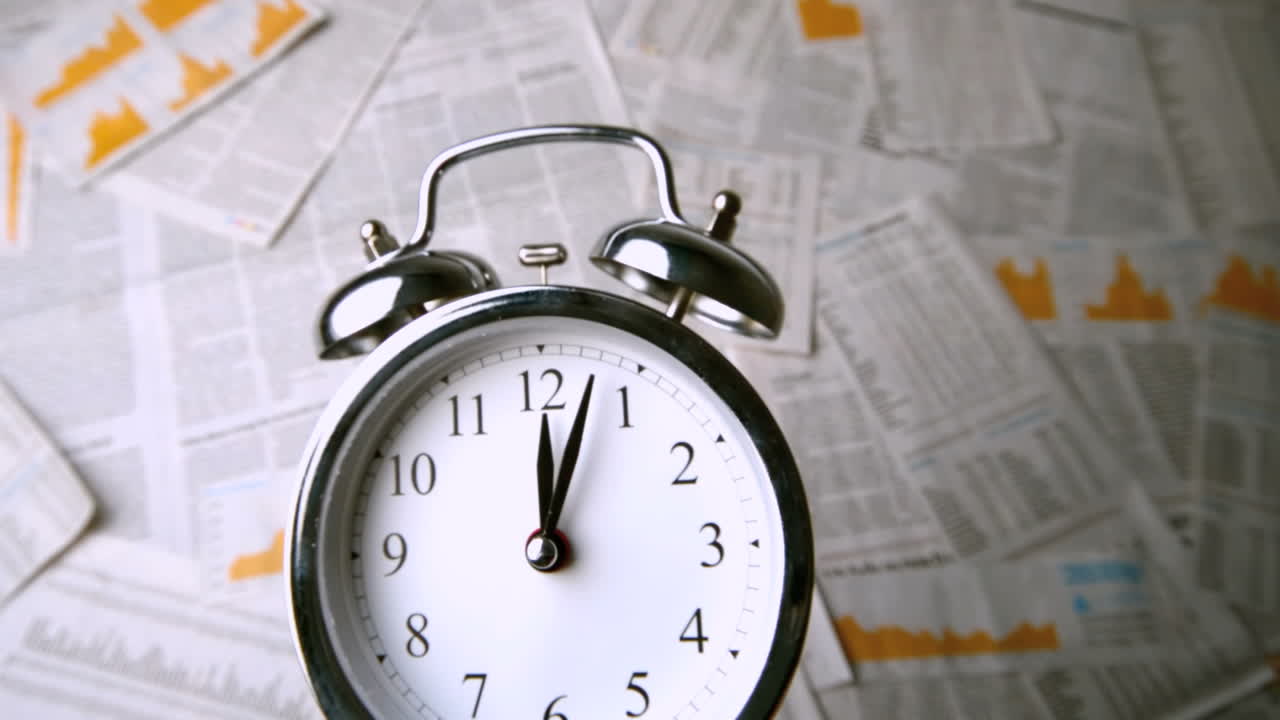 Ringing alarm clock falling over sheets of paper