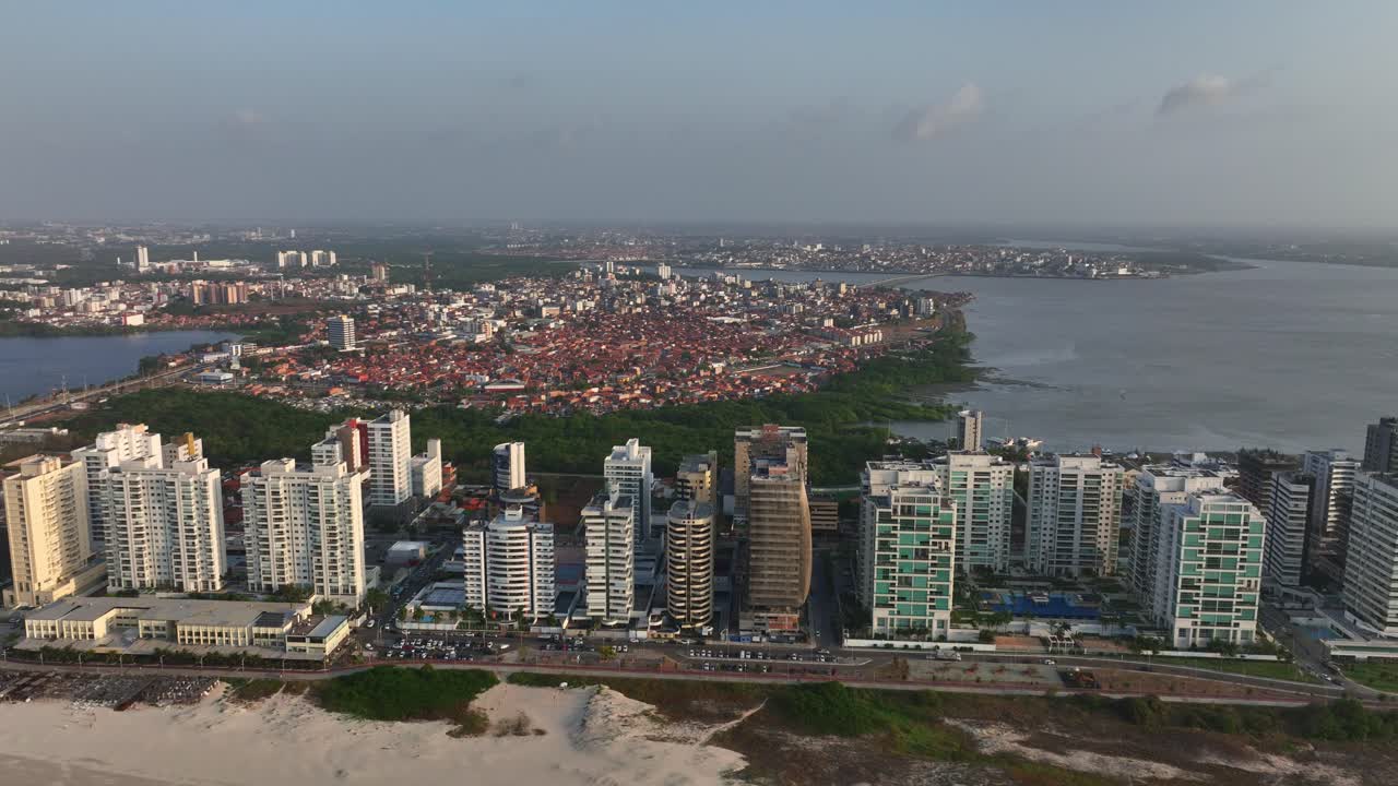 High rise buildings line the sandy coast with inland cityscape and water in Sao Luis (São Luís), Brazil. Drone aerial view