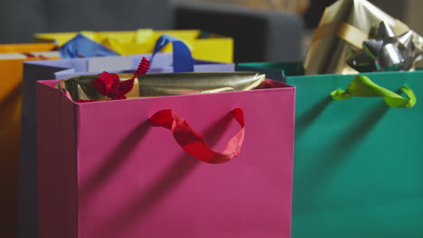 cerca de regalos envueltos en bolsas de colores con etiqueta en la mesa en el salón en casa 3