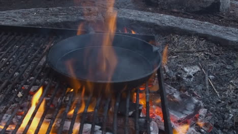 Große-Gusseisenpfanne-über-Offenem-Feuer-Eingebrannt,-Räuchern-Auf-Metallgrill