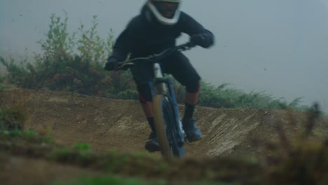 a downhill mountain biker performs a turn in the fog