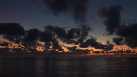 scenic sunset over the ocean with mystic dark clouds, view from the ship sailing with wide open view, calm recreation cruise ship holiday