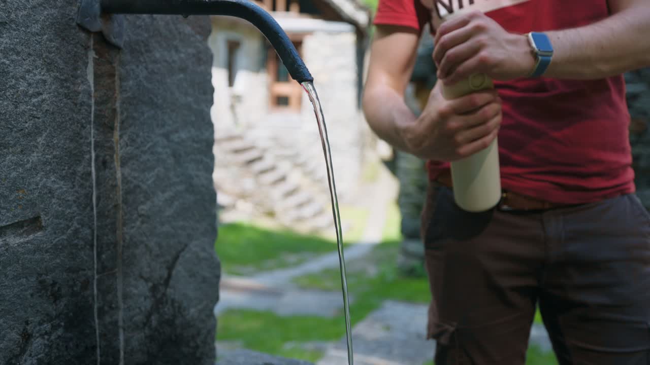 hombre llenando un vaso con agua de la fuente del hidrante - cámara lenta