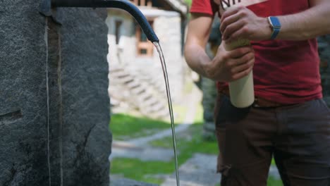 man filling a tumbler with water from hydrant fountain - slow motion