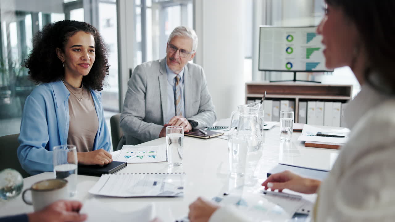 A diverse group of businesspeople shake hands at a meeting table.