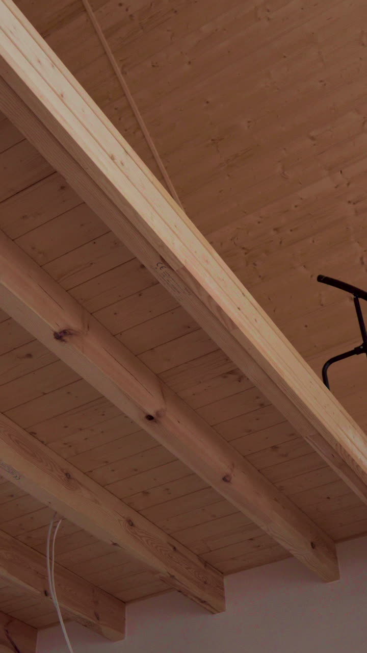 L'immagine mostra le travi in legno che formano la struttura del soffitto di una casa. Ideale per studi architettonici, progetti di costruzione o presentazioni di interior design.