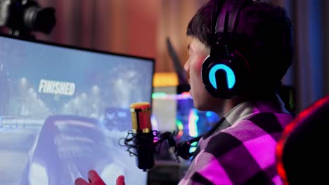 close up back view of asian boy streamer feeling disappointed fails car racing game over on personal computer.  live stream video game, desk illuminated by rgb led strip light