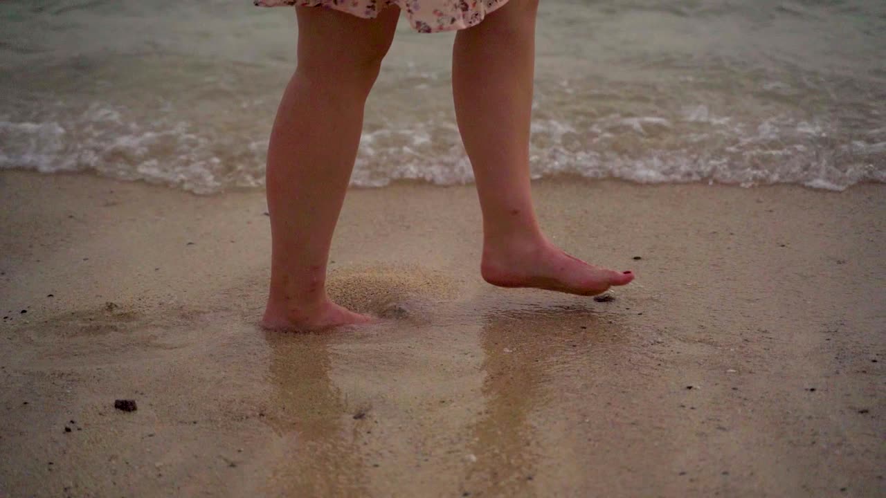 Slow motion shot of female person walking on sandy beach shore