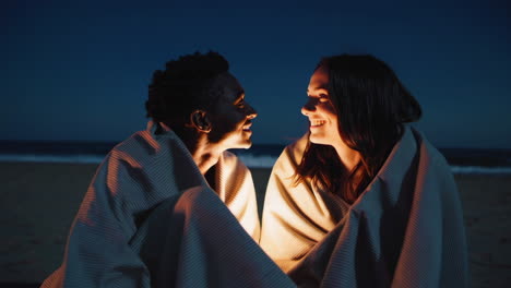 couple cozying up on the beach at night