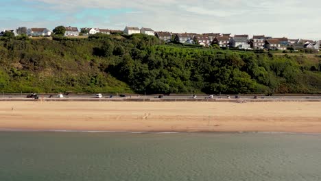 Toma-Panorámica-Con-Drones-De-La-Playa-De-Exmouth,-Devon-Desde-El-Agua-Que-Muestra-El-Paseo-Marítimo-Y-La-Zona-Residencial-De-Foxhole-Hill-En-La-Cima-Del-Acantilado