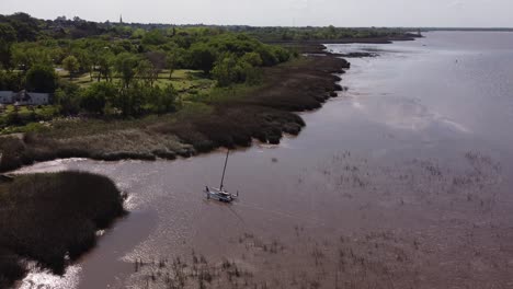 aerial track shot of person carrying catamaran out of river plate after ride on water during sunset - buenos aires,south america