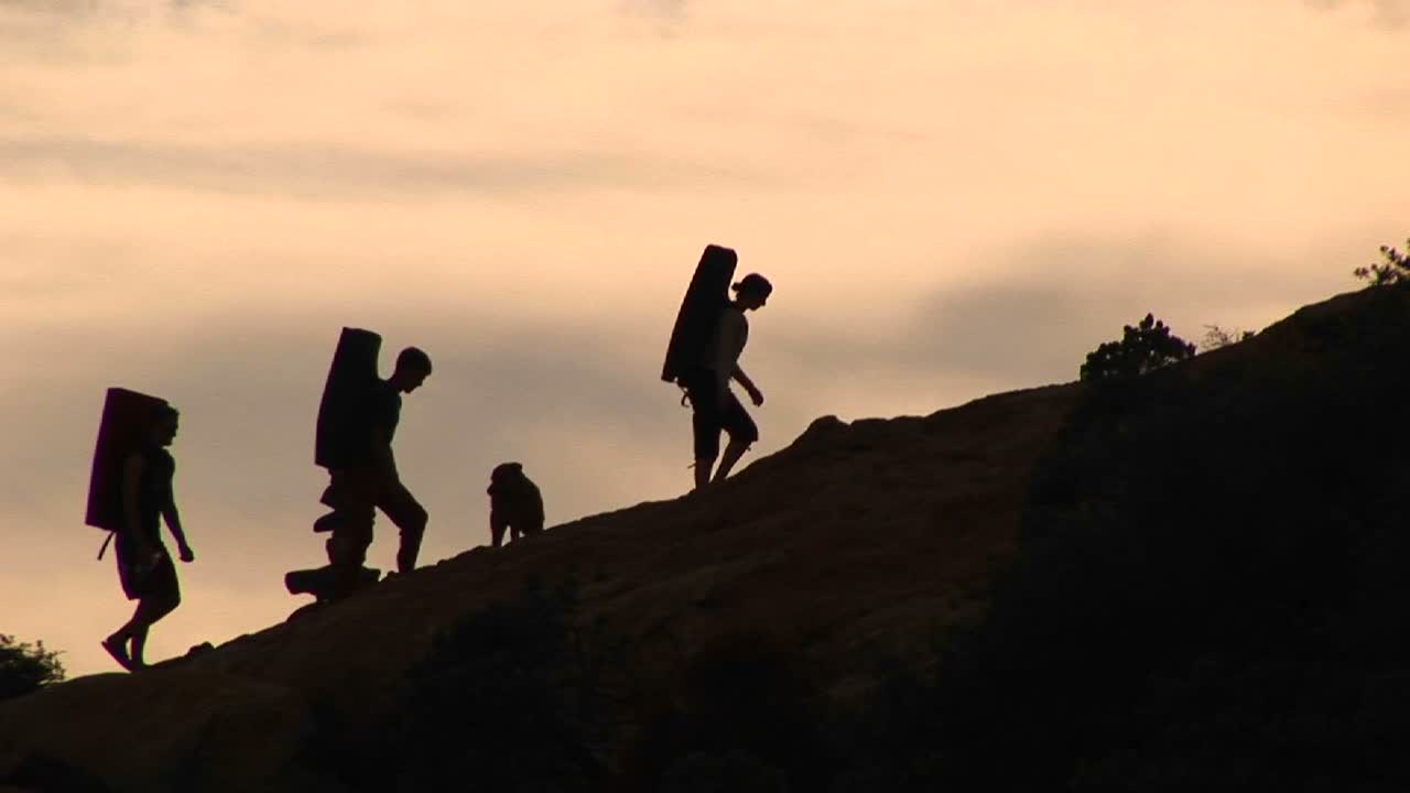 윤곽이 있는 백패커 그룹과 암벽을 오르는 개의 중간 사진