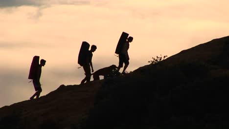 Mediumshot-De-Un-Grupo-De-Silueta-De-Mochileros-Y-Un-Perro-Escalando-Una-Estructura-De-Roca