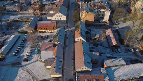 aerial establishing view of kuldiga old town , houses with red roof tiles, liepajas street, sunny winter day, travel destination, wide drone shot moving forward, tilt up