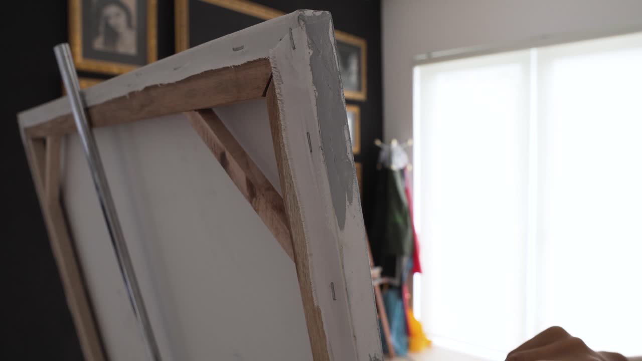 팔레트가 있는 예술가의 손이 캔버스의 측면을 페인트합니다.