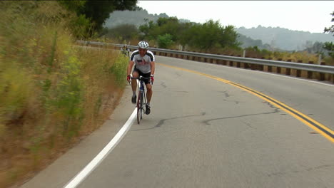 Los-Ciclistas-Pedalean-Alrededor-De-Una-Curva-De-Montaña.