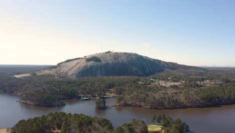 Aerial-drone-shot-slowly-circling-Stone-Mountain-Park-in-Atlanta,-Georgia-on-a-sunny-day-with-the-city-in-the-background