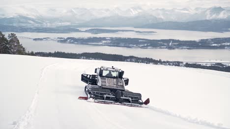 snowcat driving over large snow-covered mountains, preparing the slopes