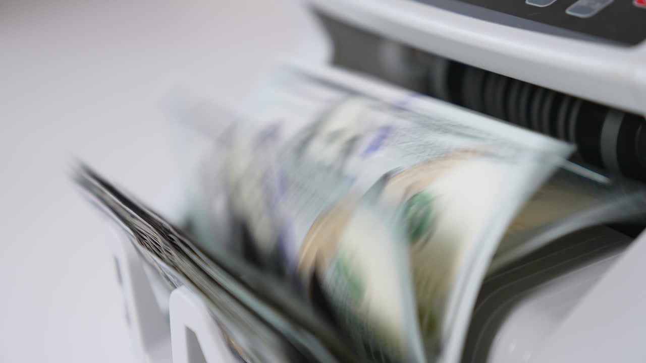 American banknotes rotating quickly in the slot of cash counting machine. Close up. Blurred background.