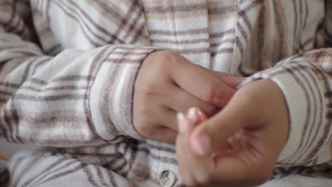 close-up of hands buttoning a plaid shirt cuff