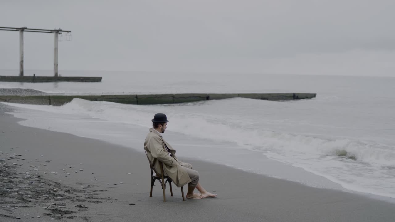 낮이 밤으로 변하기 직전에 구름이 쌓인 날 바 ⁇ 가에 앉아 있는 외로운 남자