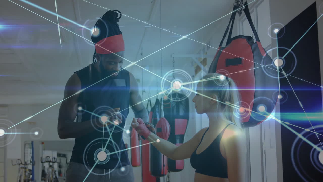 Female client and male trainer bumping fists in gym area, displaying holographic network overlay