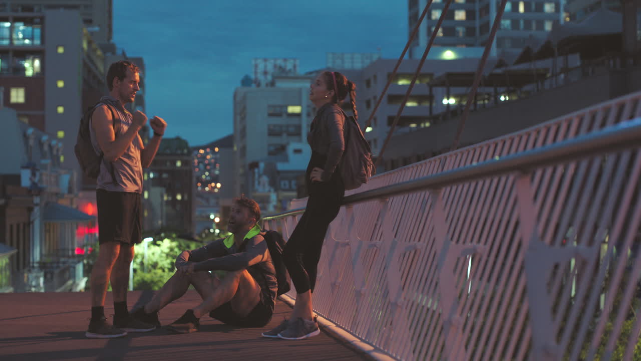 Amis se détendant après une course de nuit sur un pont de la ville