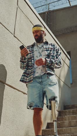 man with prosthetic leg using phone on stairs