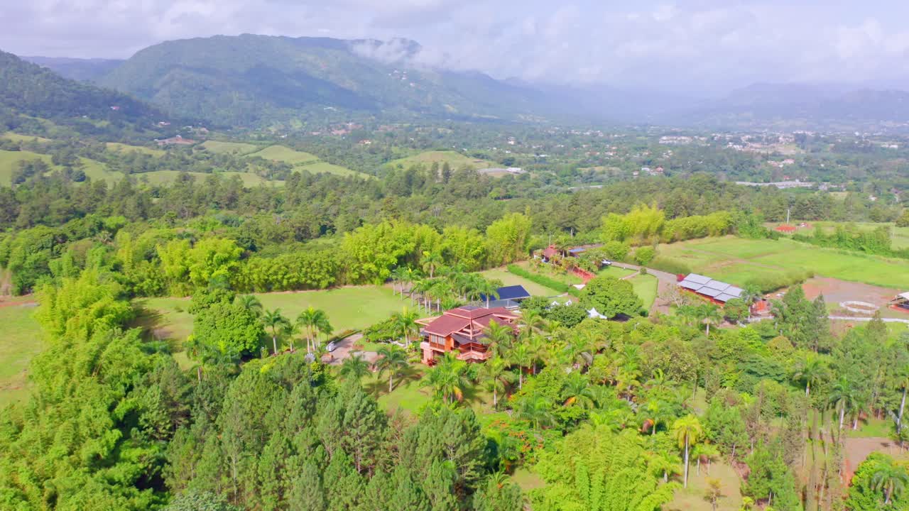 Vista aérea de uma pequena vila rodeada por paisagem verdejante e montanhas em Jarabacoa, República Dominicana.