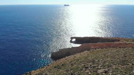 drone disparó sobre rocas en la naturaleza y hacia una ventana de piedra y una filfla - una pequeña isla en el mar mediterráneo de malta