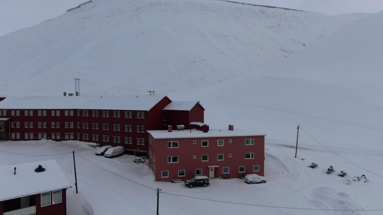 Drone view in Svalbard vertical lift in Longyearbyen town showing houses in a snowy area in Norway