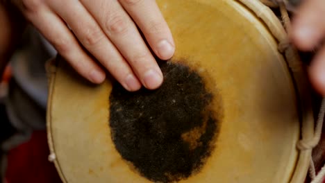 close up of hands of a man playing a drum.