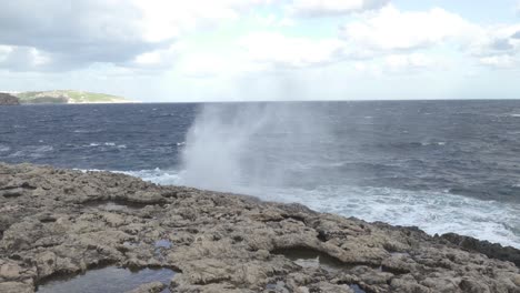 géiser de salpicaduras de agua cerca de la cueva de la laguna de coral en malta en un día soleado en invierno