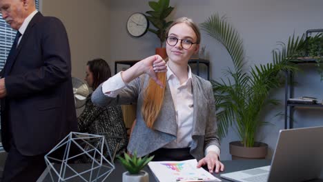 unhappy young woman secretary making thumb down gesture expressing discontent, disapproval in office