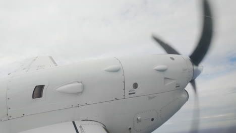 Raindrops on window, inside airplane looking out at wing and propellor