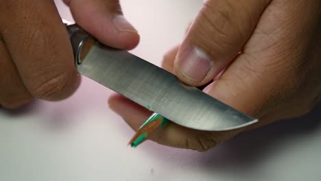 Footage-of-hands-slowly-sharpening-a-pencil-and-some-coloured-pencils-with-a-sharp-knife