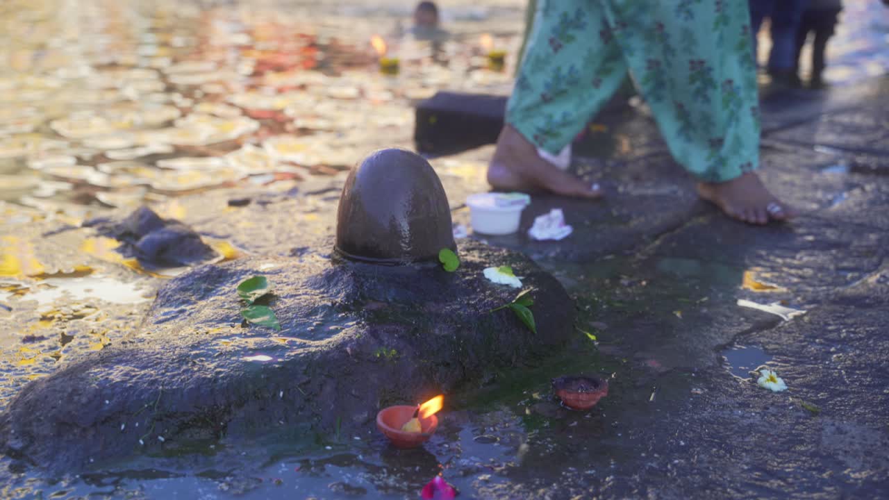 Woman devotee offering holy water of godavari river to Shiva Lingam at Ganga Ghat, Maha Kumbh 2027, Nashik, Maharashtra