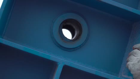 close-up of a blue metal part with a hole and bearing