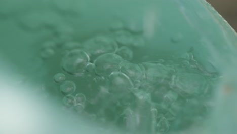 water dripping into a green bucket in slow motion